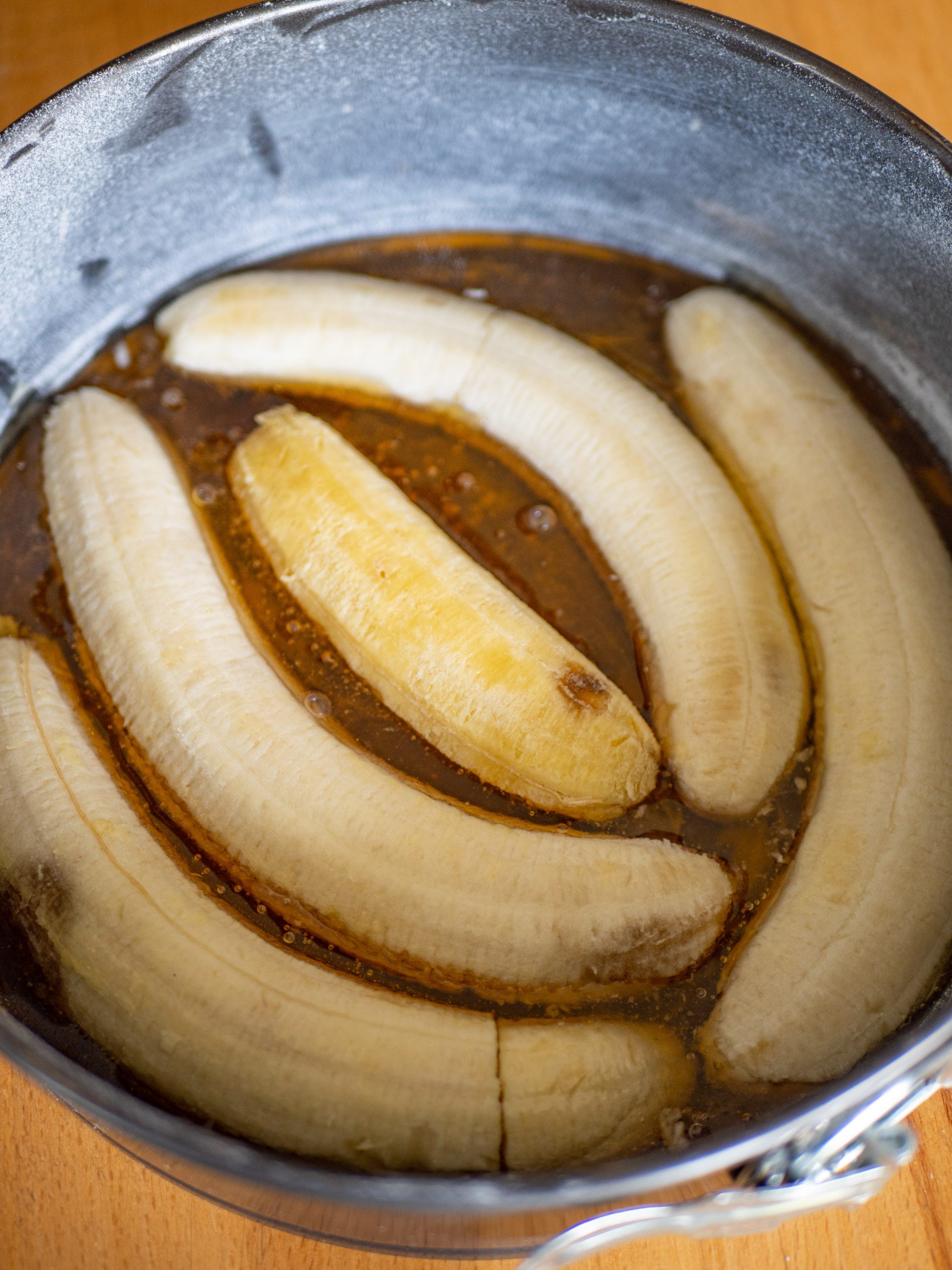 5. Beurrer et fariner un moule rond de 20 cm de diamètre. Étaler le miel en une couche fine puis répartir les moitiés de bananes.