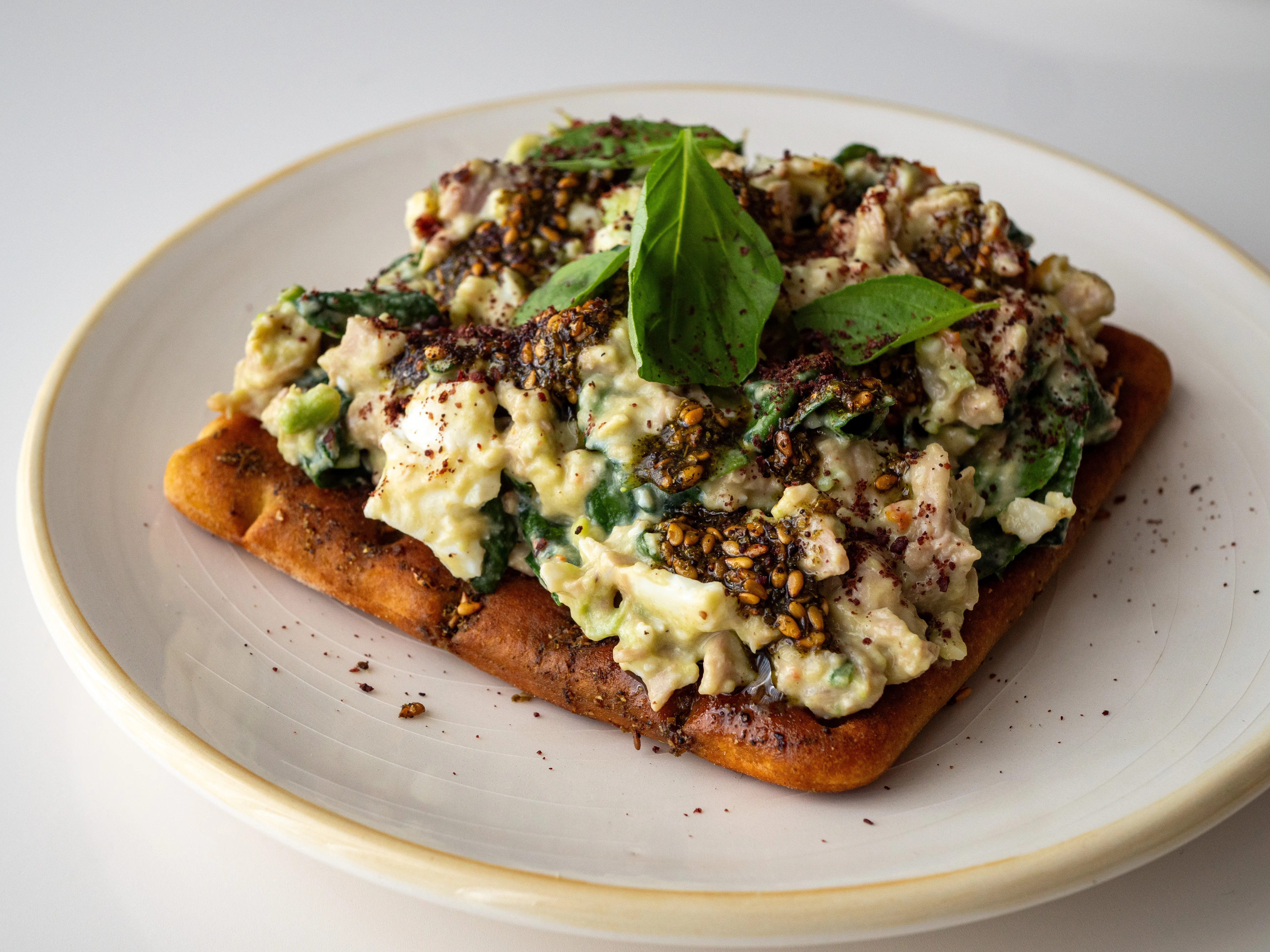 Recette de chopped salad au poulet rôti, avocat, œufs mollets, zaatar, tahini & sumac